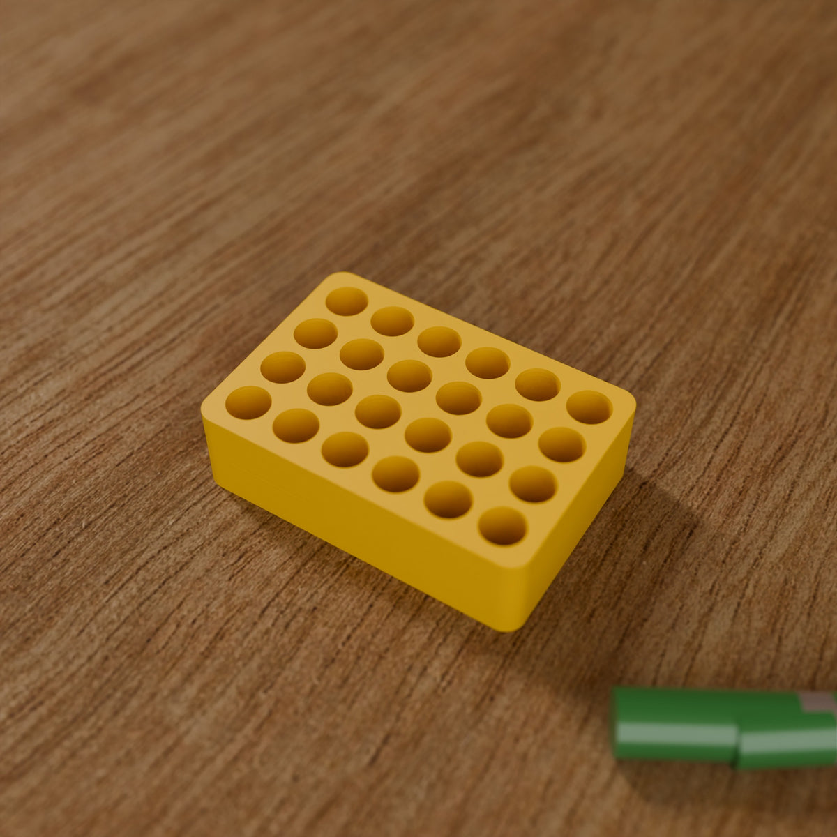 Battery Organizer (24x AAA) in Bright Yellow PLA, next to batteries on a wooden workbench