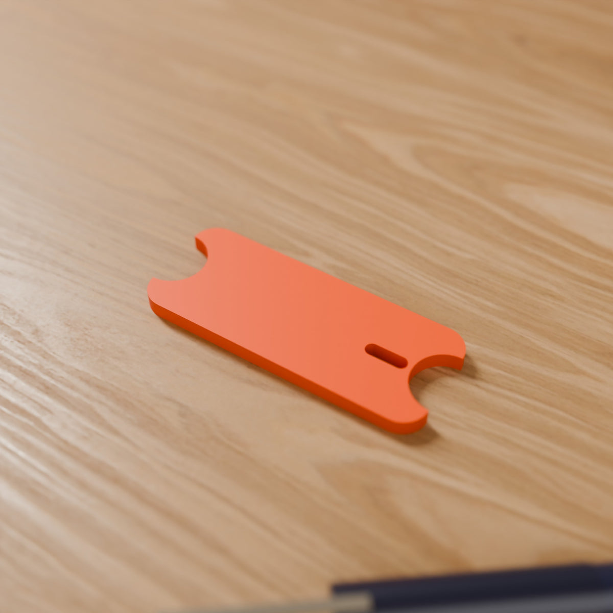 Cord Wrap Winder (Standard) in Bright Orange PLA, on a wooden desk