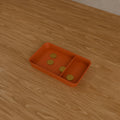 Desk Catch-All Tray in Matte Terracotta PLA, holding coins on a wooden desk