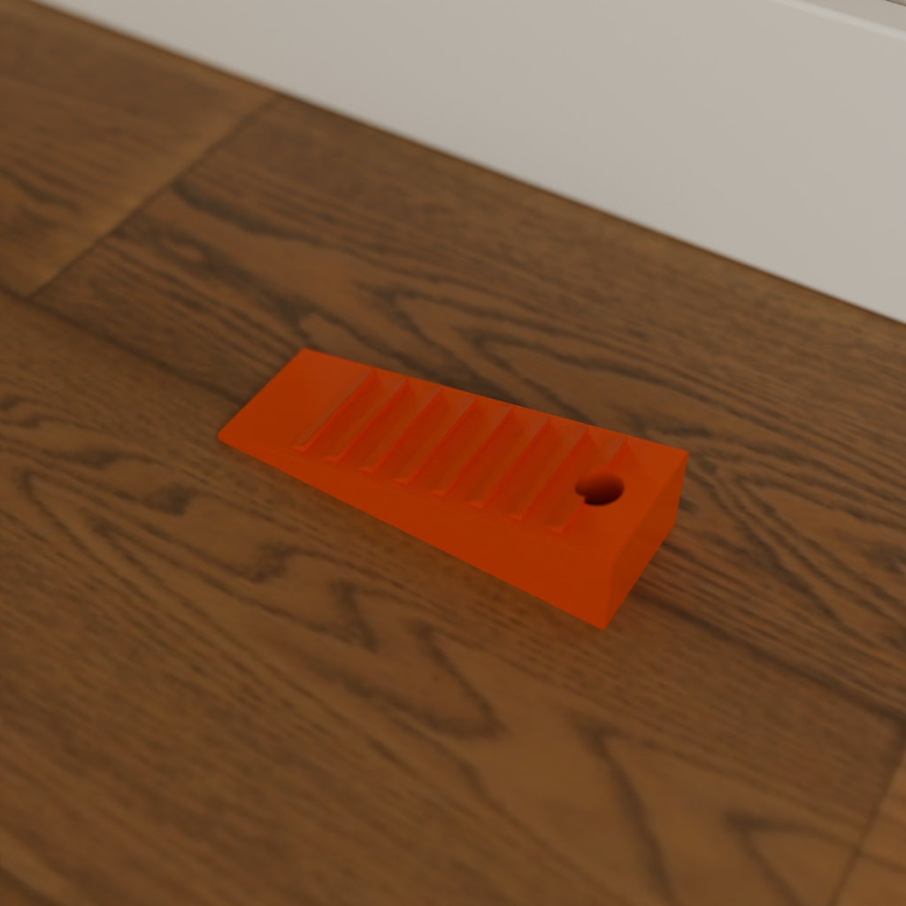 Grippy Door Stop Wedge in Bright Orange PETG, on a wooden floor