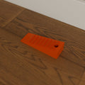 Grippy Door Stop Wedge in Bright Orange PETG, on a wooden floor