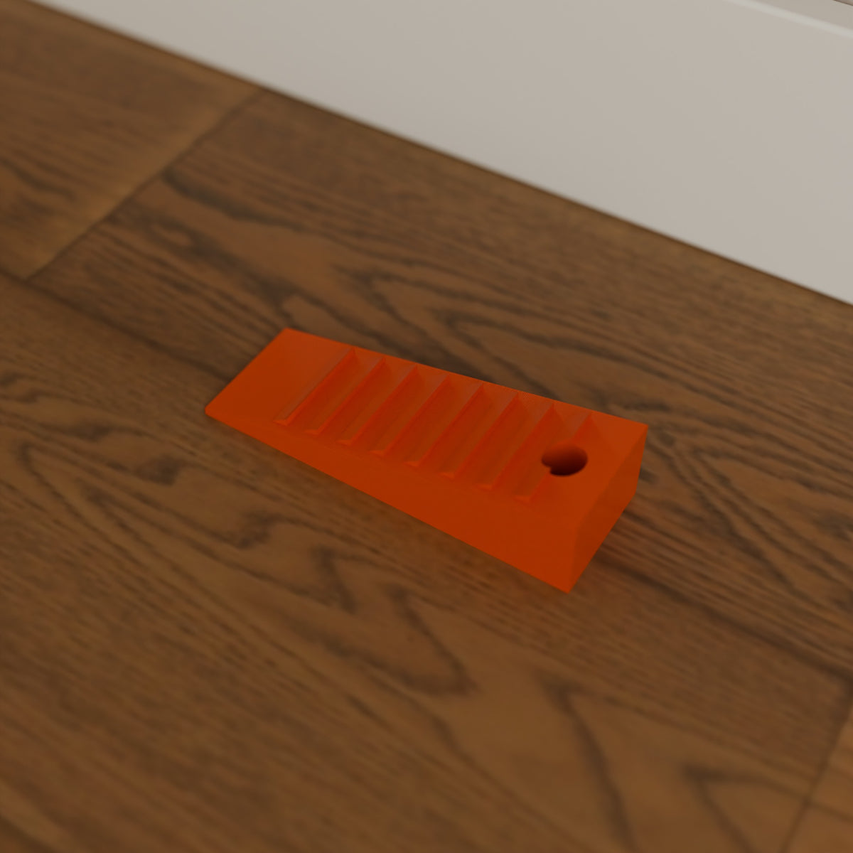 Grippy Door Stop Wedge in Bright Orange PETG, on a wooden floor
