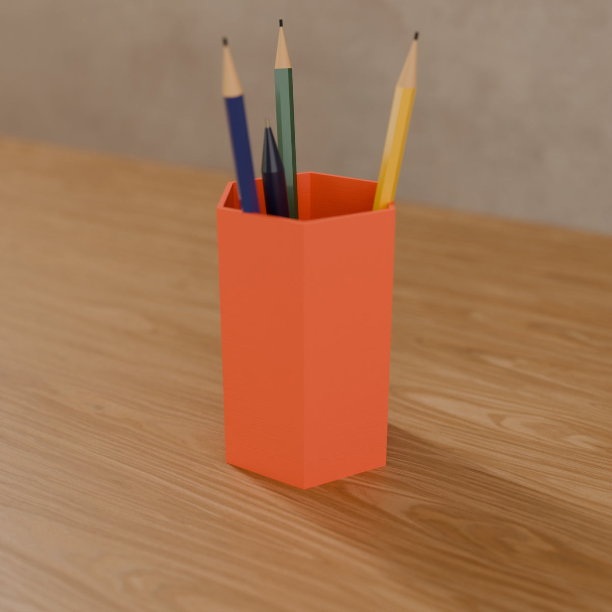 Hex Pen Cup (Tall 120 mm) in Matte Coral PLA, holding pencils on a wooden desk