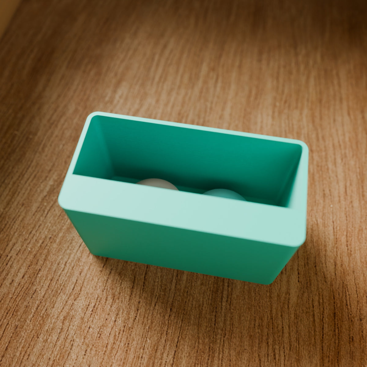 Modular Storage Bin (1x2) in Matte Teal PLA, on a wooden surface