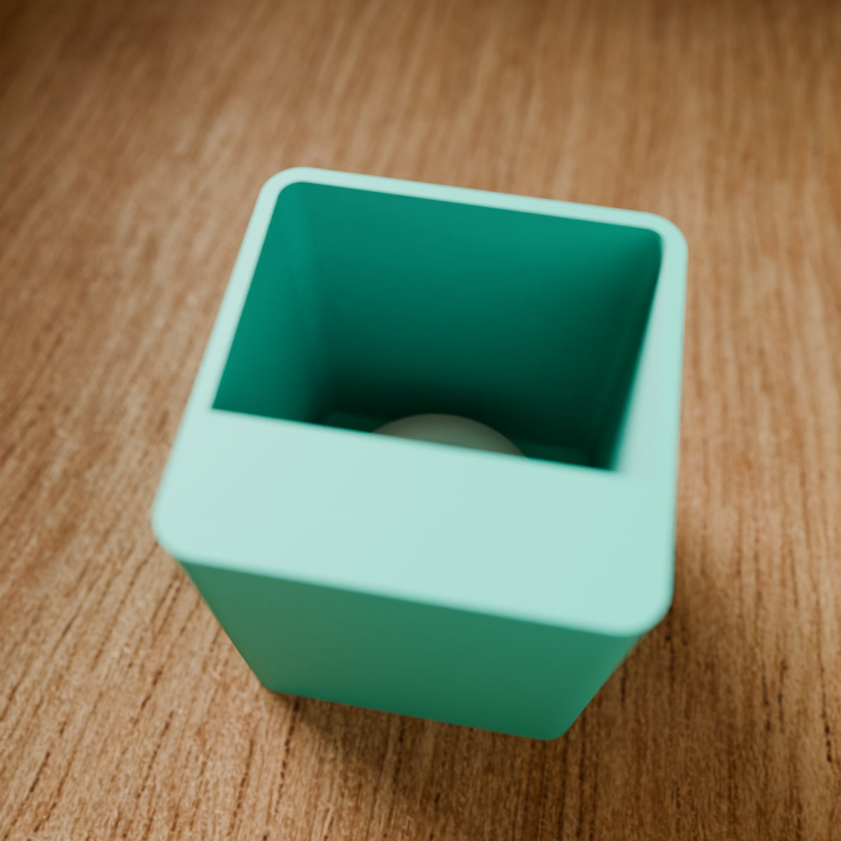 Modular Storage Bin (1x1) in Matte Teal PLA, on a wooden surface