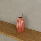 Ripple Bud Vase in Silk Rose Gold PETG, with a dried stem on a wooden shelf