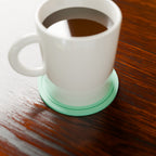 Ripple Ring Coaster in Matte Mint PLA, under a coffee mug on a wooden table