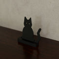 Spooky Silhouette Shelf Sitter (Sitting cat) in Matte Black PLA, on a dark wooden shelf