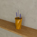 Twisted Hex Vase in Silk Gold PETG, holding dried lavender on a wooden shelf