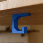 Under-Desk Headphone Hook in Bright Blue PLA, mounted under a wooden desk