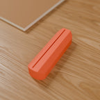 Wave Photo & Postcard Stand in Matte Coral PLA, on a wooden desk